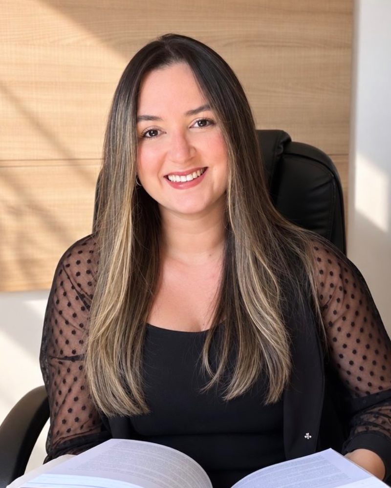 Thaynara Gomes sentada no consultório com um livro aberto