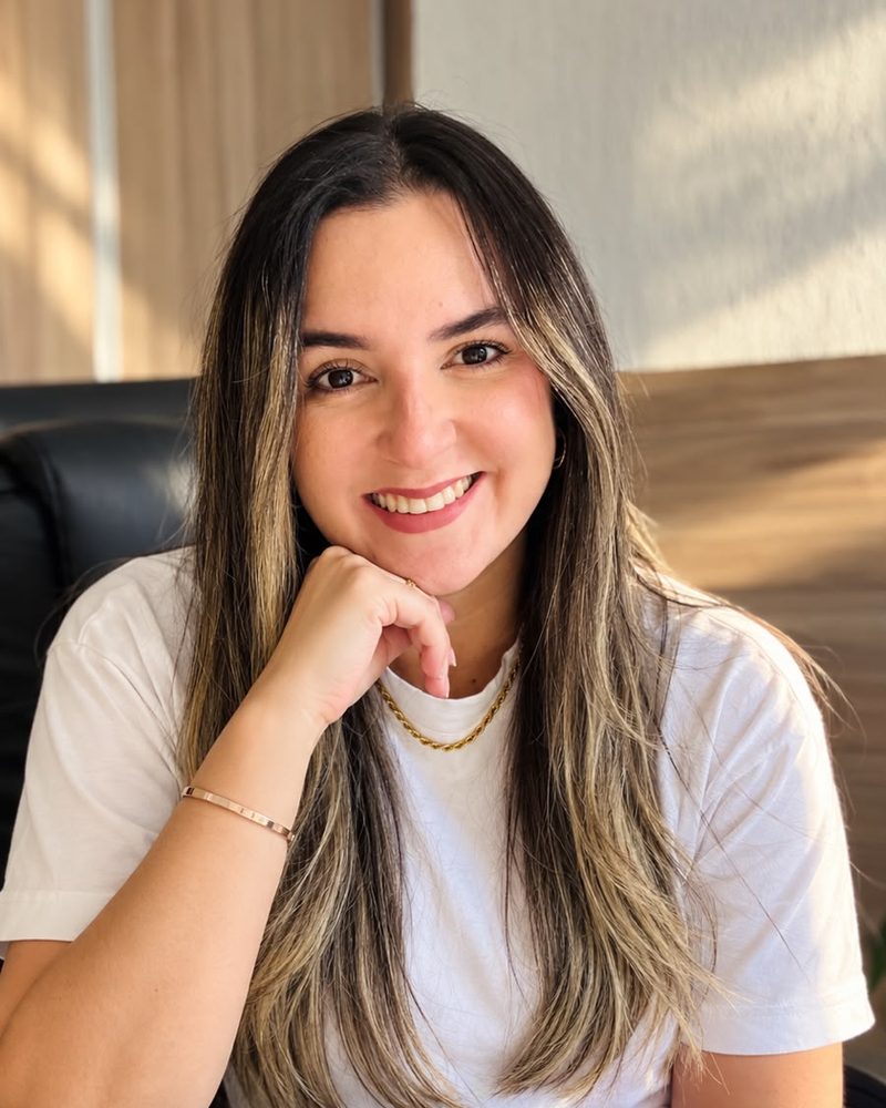 Thaynara Gomes de camiseta branca, sorrindo no consultório